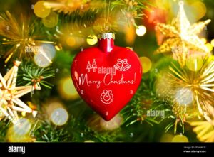 boule-de-noel-en-forme-de-coeur-avec-inscription-merry-christmas-accrochee-a-un-sapin-de-noel-photomontage-3dam82f